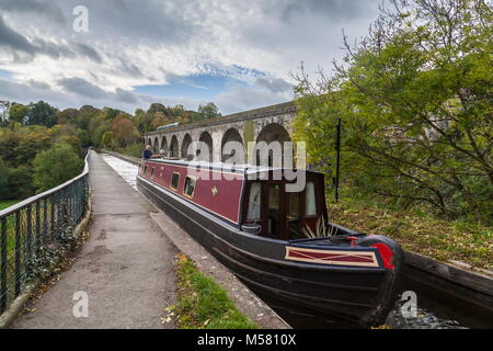 A narrow boat crosses from England into Wales across the Chirk Aqueduct during early Autumn while a train crosses the Henry Robertson built Viaduct Stock Photo