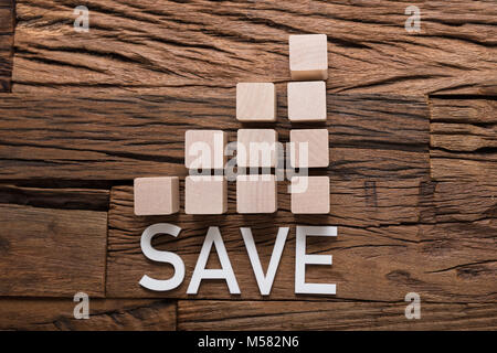 Closeup of save text by increasing bar graph blocks on wooden table Stock Photo