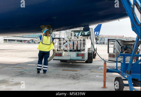 Female lav agent. Girl station attendant emptying a lavatory system of plane airplane aeroplane on tarmac apron airside. Woman ramper doing the lavs. Stock Photo
