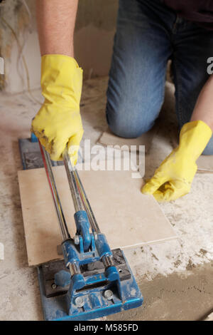 Tiler cutting ceramic tiles during floor installation Stock Photo