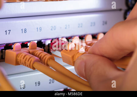 Cropped image of hand connecting network cable plug to server Stock Photo