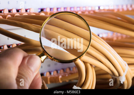 Cropped image of hand examining network cables in server room Stock Photo
