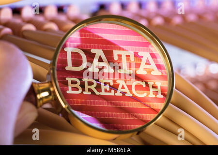 Cropped image of hand analyzing data breach through magnifying glass over cables in server room Stock Photo