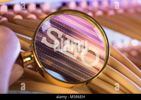 Cropped image of hand analyzing SEO through magnifying glass over cables in server room Stock Photo