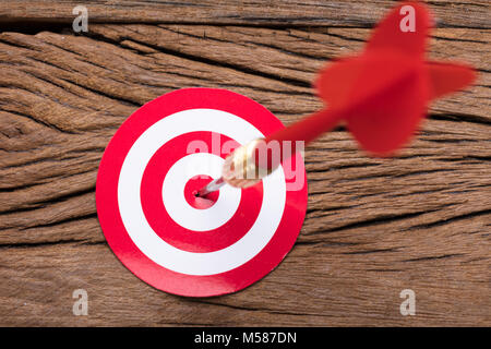 Closeup of red arrow in dartboard on wooden table Stock Photo