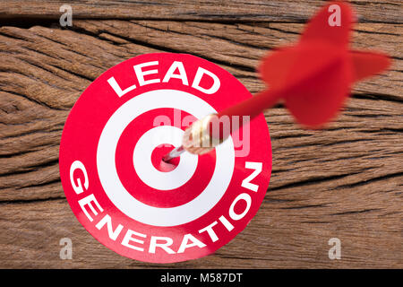 Closeup of red arrow in dartboard on wooden table Stock Photo