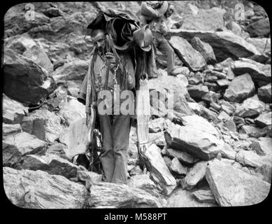 Grand Canyon Matthes Survey of . BLACK AND WHITE GLASS LANTERN SLIDE. TWO MEN ON ROCKS, LOADED WITH SADDLES AND OTHER EQUIPMENT. USGS LABEL ATTACHED CIRCA 1902. WITH A GROUP OF SLIDES FROM THE MATTHES SURVEY EXPEDITION IN THE GRAND CANYON - CIRCA 1902 Stock Photo