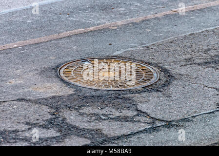 Manhole cover in the middle on a footpath Stock Photo