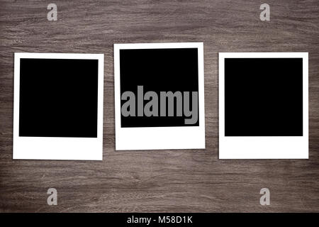 three blacked-out instant photo print templates on wooden background Stock Photo