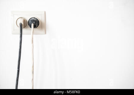 Electric socket with two stuck electric plugs on a white wall. Power socket and plug Stock Photo