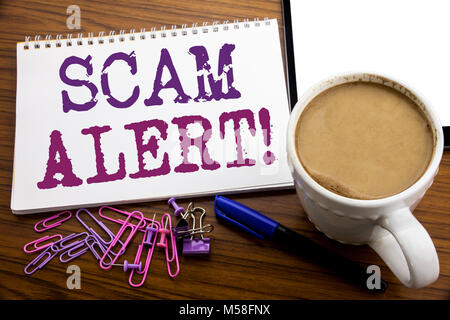 Hand writing text caption inspiration showing Scam Alert. Business concept for Fraud Warning written on note paper on wooden background with coffee an Stock Photo