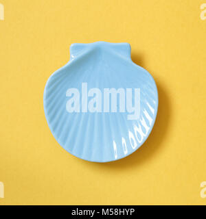 Shell-shaped plate isolated on yellow background Stock Photo