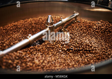 Stainless steel arms mixing freshly roasted coffee beans in large stainless steel cooling drum where the beans are cooled down before packaging or sto Stock Photo