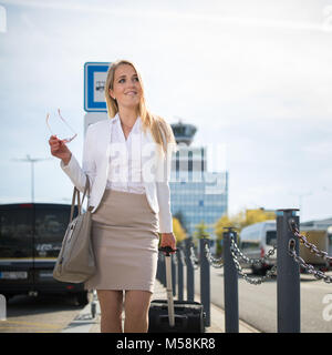 Young female passenger at the airport, walking to he departure terminal from a parking lot (color toned image) Stock Photo