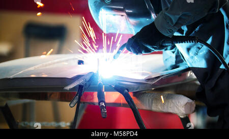 Welding industrial: worker in helmet repair detail in car service Stock Photo