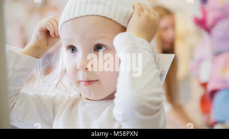 Little girl trying on white caps Stock Photo