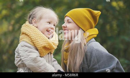 Little blonde girl with her mommy in autumn park - play and clap hands, close up Stock Photo