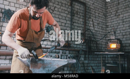 Blacksmith with hammer in forge creating steel knife Stock Photo
