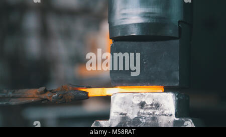 Automatic hammering - blacksmith forging red hot iron on anvil, extreme close-up Stock Photo