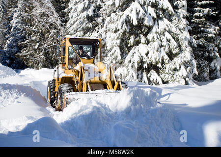 02/19/2018 Snow event. A Caterpillar 950 rubber tired articulated loader clearing snow on a mountain road north of Noxon, in Sanders County Montana. Stock Photo