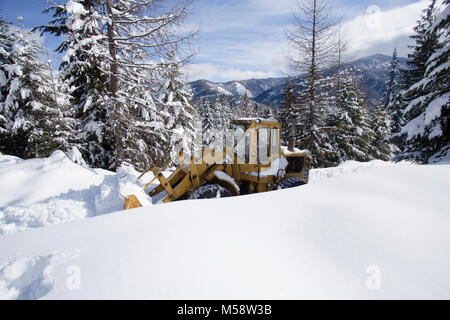02/19/2018 Snow event. A Caterpillar 950 rubber tired articulated loader clearing snow on a mountain road north of Noxon, in Sanders County Montana. Stock Photo