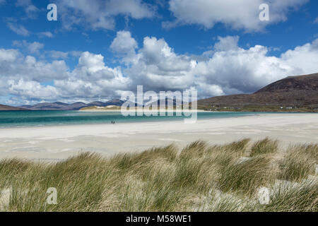 Walkers on the beach at Seilebost, Isle of Harris, Outer Hebrides, Scotland. With the dunes of Luskentyre beach in the distance. Stock Photo