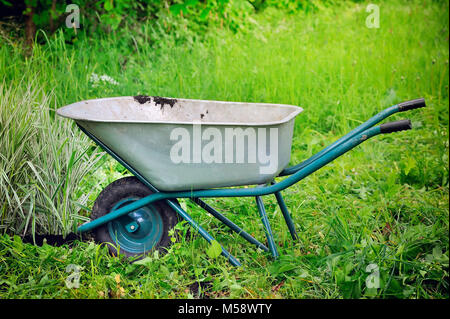 Old wheelbarrow on a green grass field background Stock Photo