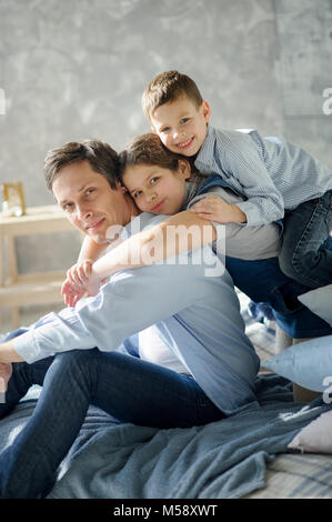 Father of three children. The young man sits in an environment of two daughters and the son. All have on faces happy smiles. Stock Photo