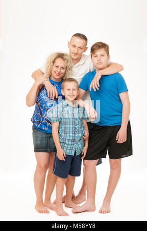 Full body portrait of a young family with father, mother and two boys in front of white background. Stock Photo