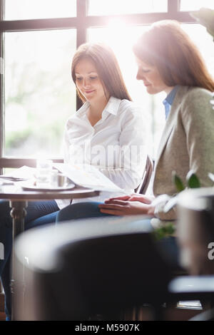 Young businesswomen reading brochure at cafe table Stock Photo
