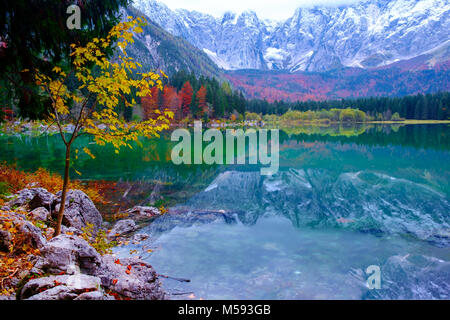 Beautiful Lago di Fusine mountain lake in autumn and Mangart mountain in the background at sunset in north Italy alps , Europe Stock Photo