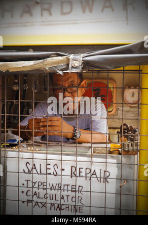Manila,Philippines-October 24,2016: Small dealer repairs clocks and small electronic gadgets in his mini street booth on October 24, Manila,Philippine Stock Photo