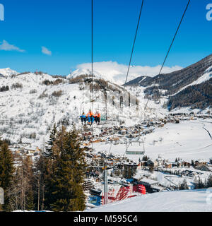 La Thuile, Italy - Feb 18, 2018: Chairlift at Italian ski area on snow covered Alps and pine trees during the winter - winter sports concept Stock Photo