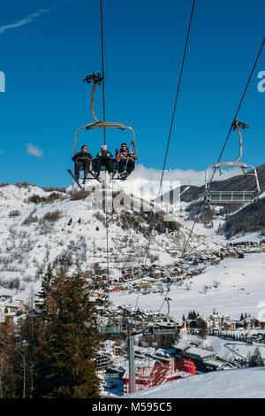 La Thuile, Italy - Feb 18, 2018: Chairlift at Italian ski area on snow covered Alps and pine trees during the winter - winter sports concept Stock Photo