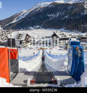 La Thuile, Italy - Feb 18, 2018: Ascending conveyor belt to a beginners run for children and parents in ski resort with mountains in background Stock Photo