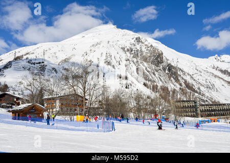 La Thuile, Italy - Feb 18, 2018: Ascending conveyor belt to a beginners run for children and parents in ski resort with mountains in background Stock Photo