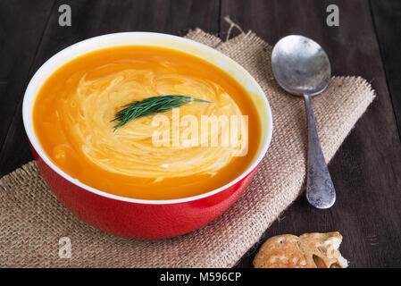 Pumpkin and sweet potatoes soup with sour cream, dill and pumpkin bread on dark wooden table Stock Photo