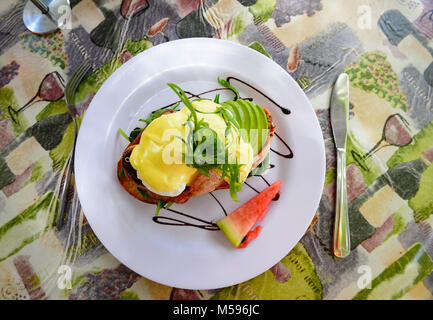 Tasty classic dish of eggs Benedict on a white plate, nicely presented Stock Photo
