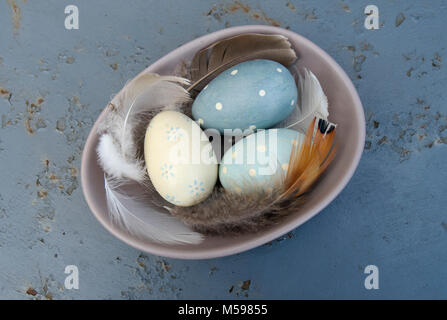 Wooden eggs and feathers in a ceramic bowl Stock Photo