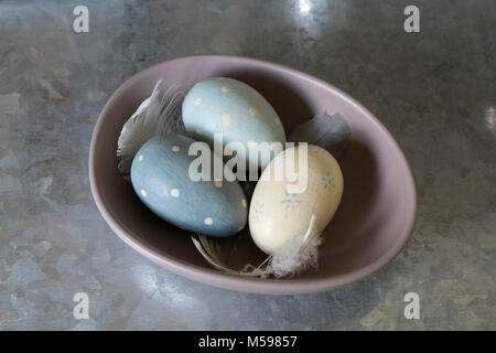 Wooden eggs and feathers in a ceramic bowl Stock Photo