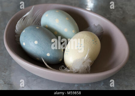 Wooden eggs and feathers in a ceramic bowl Stock Photo