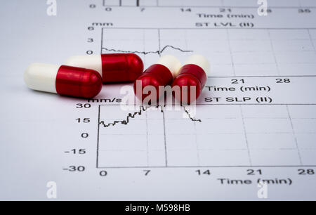 EKG or ECG (Electrocardiogram) graph report paper. EST ( Exercise Stress Test ) result and red-white capsule pills. Package promotion for heart check  Stock Photo