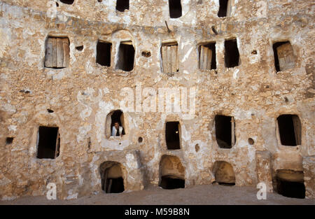 Libya. Qasr Al-Hadj. Sahara desert. Fortified stone granaries to store the harvest. Man looks through window. Stock Photo