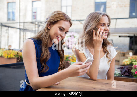 young women with smartphones and coffee at cafe Stock Photo