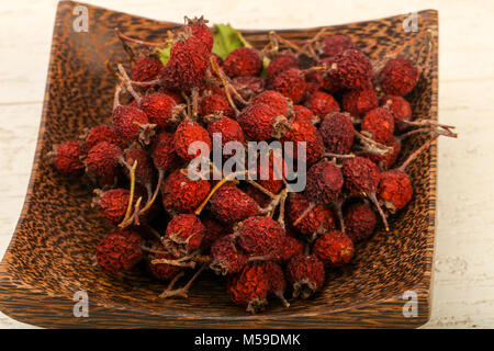 Dry hawthorn heap in the bowl over wooden background Stock Photo