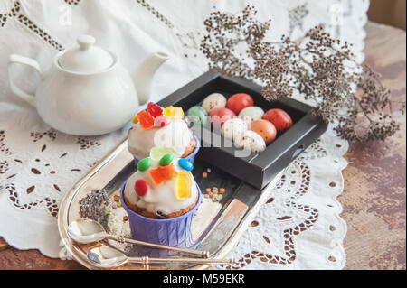 Easter cakes with icing and marmalade decoration and caramel marzipan eggs in a box. Easter decor. Close up. Copy space. Stock Photo