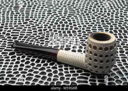 Biliard smoking tobacco pipe made from sea foam Meershaum mineral sepiolite against the background of imitation crocodile skin of black and white tone Stock Photo