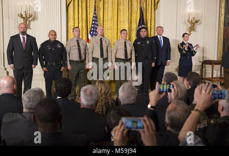 February 20, 2018 - Washington, District of Columbia, United States of America - United States President Donald J. Trump stands with District Attorney Investigator Chad Johnson, San Bernardino County District Attorney's Office(left), Detective Brian Olvera, San Bernardino Police Department(2nd left), Deputy Shaun Wallen, San Bernardino County Sheriff's Department(3rd left), Detective Bruce Southworth, San Bernardino County Sheriff's Department(3rd right), Corporal Rafael Ixco, San Bernardino County Sheriff's Department(2nd right) and Officer Nicholas Koahou, Redlands Police Department(right) a Stock Photo