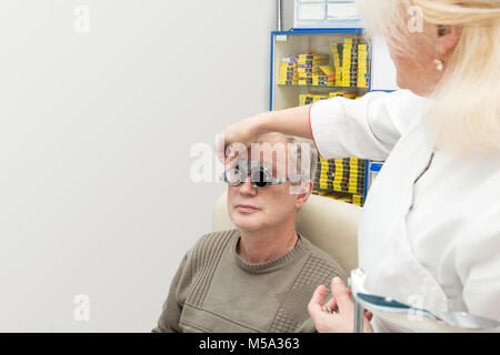 Mature man visits an ophthalmologist. Diopter selection with optometric frame Stock Photo