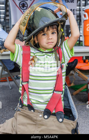 Miami Florida,Hialeah,Milander Park,Easter Egg stravaganza,fair,community Hispanic boy boys,male kid kids child children youngster,fireman,uniform,gea Stock Photo